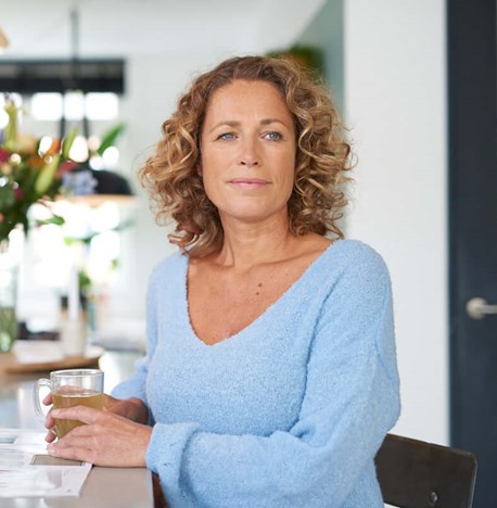 vrouw-zit-op-kruk-in-keuken-woning-met-glas-thee